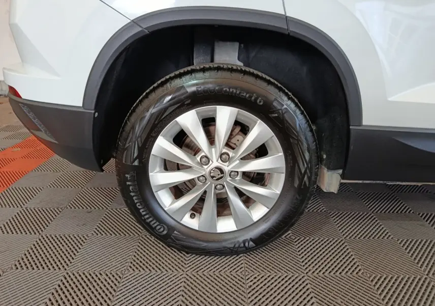 Gros plan sur la roue arrière droite argentée d'un Skoda Karoq blanc avec jante en alliage et pneu Continental.