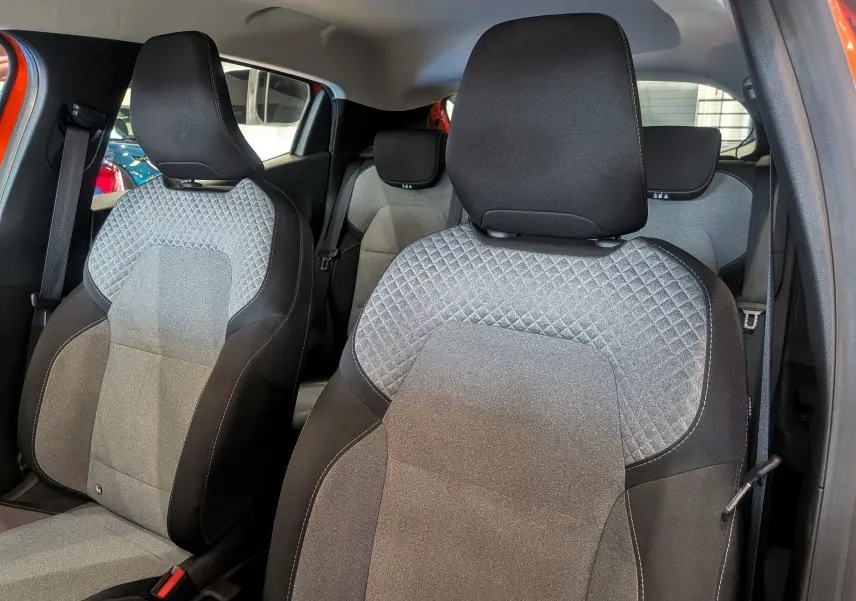 Vue intérieure des sièges avant en tissu gris avec motifs losanges du Renault Clio V Orange Valencia, côté droit ouvert.