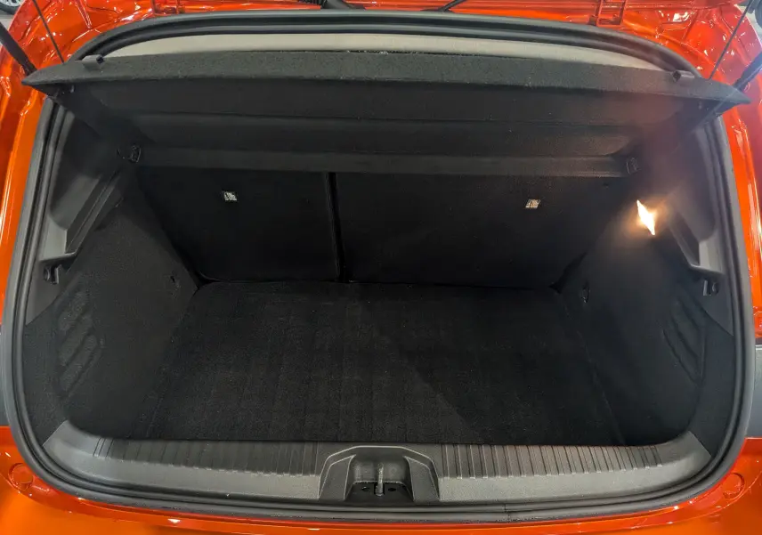 Coffre ouvert vu de l'arrière d'une Renault Clio V Orange Valencia, intérieur noir et éclairage latéral droit.