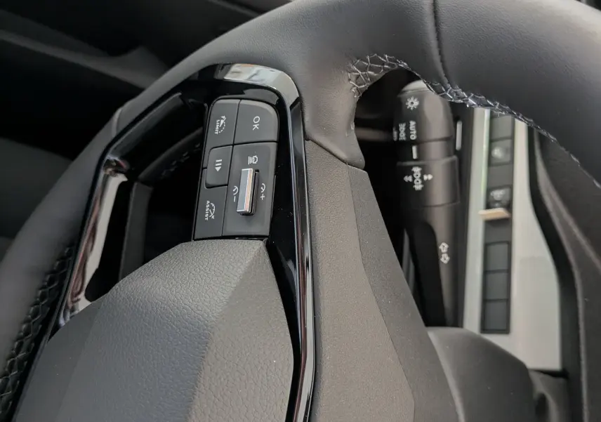 Gros plan sur le volant cuir noir du Peugeot Traveller 2026, avec commandes intégrées et logo Peugeot visible.