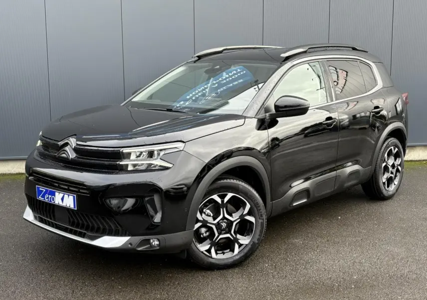 Vue 3/4 avant droite d'un Citroën C5 Aircross noir Perla avec jantes diamantées bi-ton et barres de toit noires.