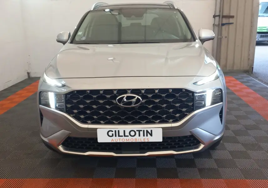 Vue avant d'un Hyundai Santa Fe gris clair avec calandre noire hexagonale et phares LED allumés.