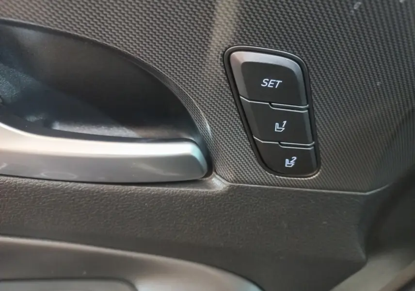 Gros plan sur la poignée intérieure et les boutons de réglage mémoire des sièges du Hyundai Santa Fe gris clair.