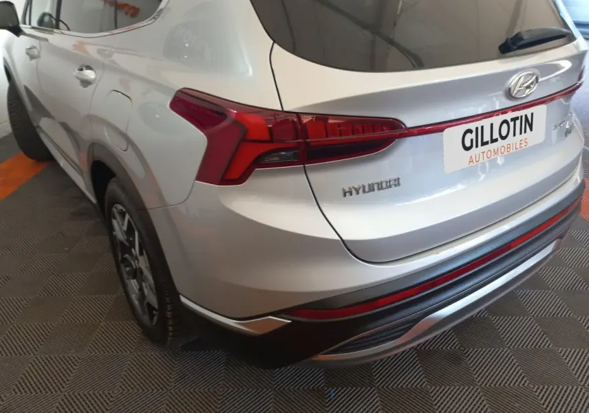 Vue 3/4 arrière droite du Hyundai Santa Fe gris clair avec feux arrière LED et jantes alliage visibles.