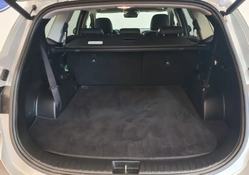 Coffre ouvert vu de l’arrière d’un Hyundai Santa Fe gris clair, montrant l’espace de chargement et la banquette arrière.