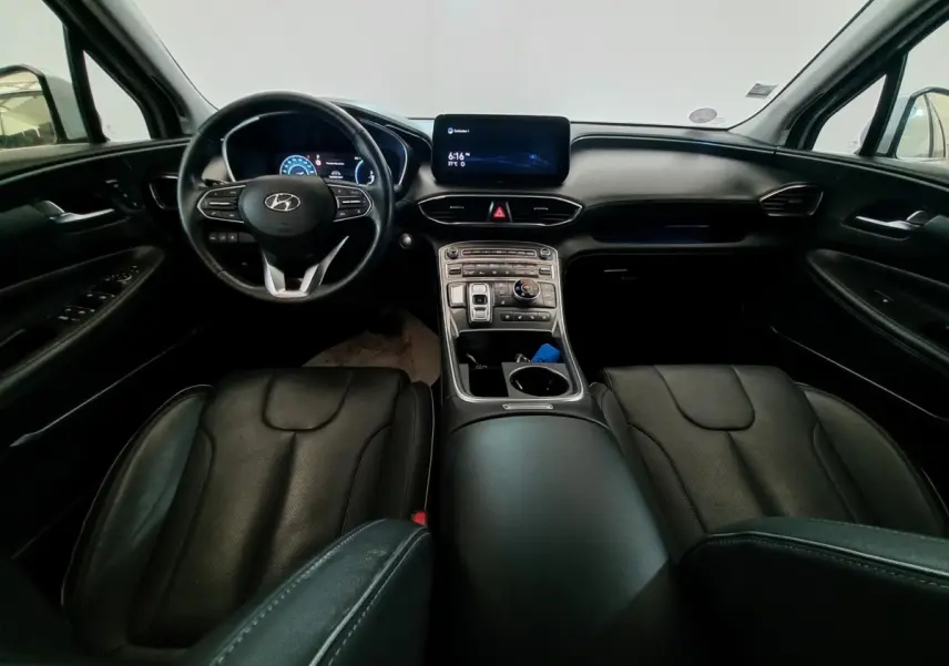 Vue intérieure avant du Hyundai Santa Fe 2021, tableau de bord et sièges en cuir noir avec écran tactile central.