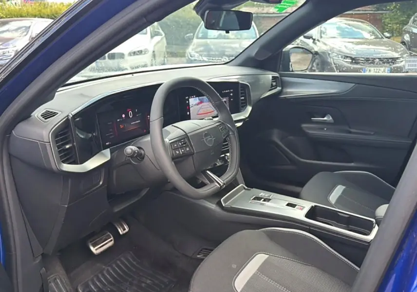 Vue intérieure côté conducteur de l'Opel Mokka Electric 156 gs bleu, avec tableau de bord numérique et volant multifonction.
