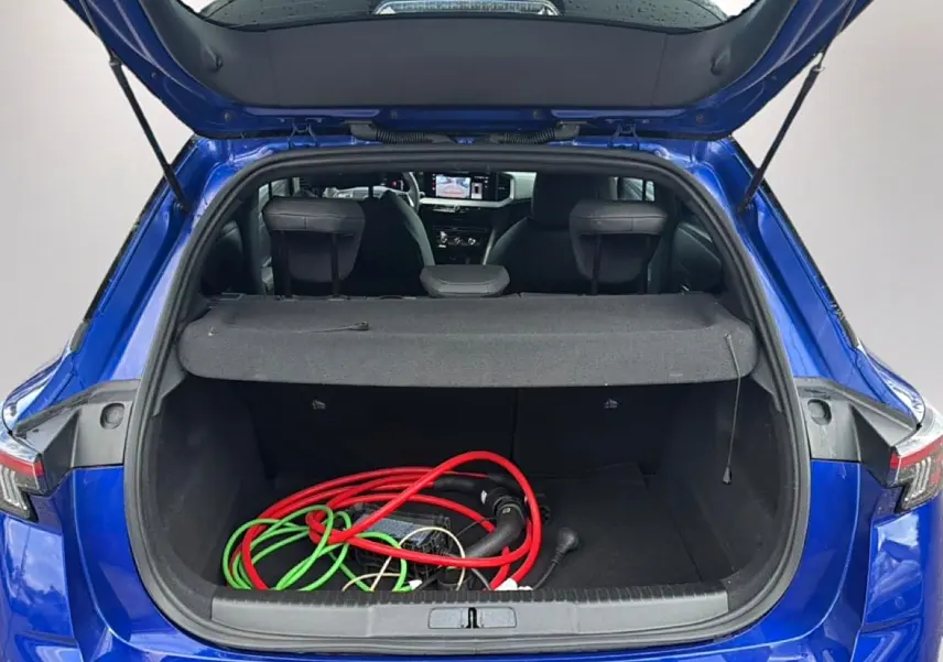 Coffre ouvert vu de l'arrière d'un Opel Mokka Electric 156 gs bleu avec câbles de recharge visibles à l'intérieur.