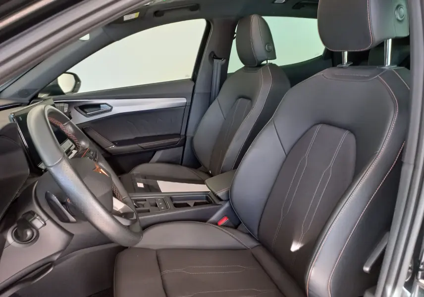 Vue intérieure côté conducteur de la CUPRA Formentor 1.4 e-HYBRID 2024 avec sièges noirs et surpiqûres orange.