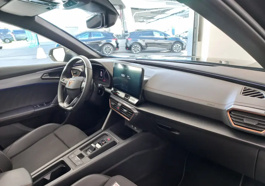 Vue intérieure côté conducteur de la CUPRA Formentor 1.4 e-HYBRID 2024 avec tableau de bord noir et écran tactile central.