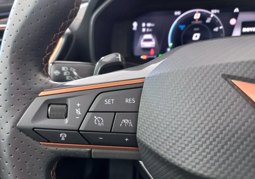 Gros plan sur les commandes à gauche du volant en cuir perforé noir avec surpiqûres orange du CUPRA Formentor 2024.