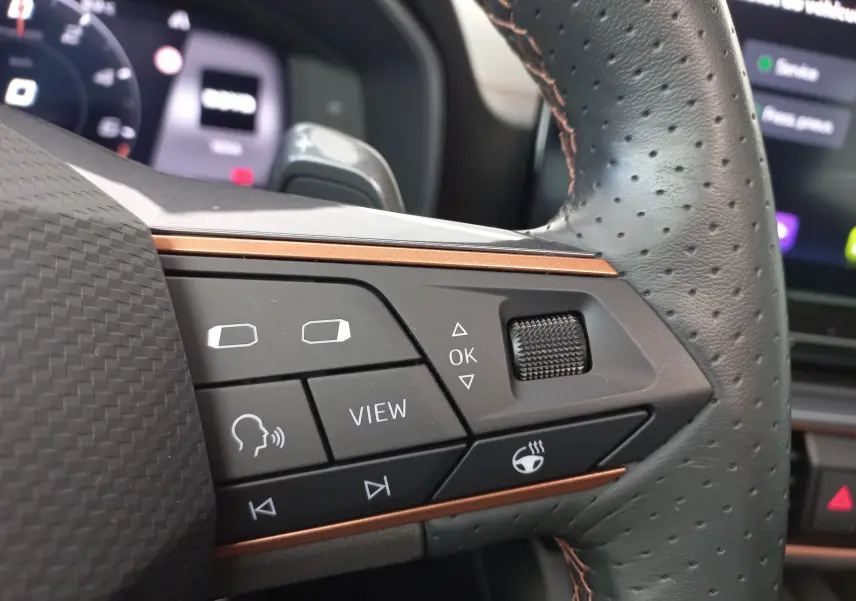 Gros plan sur les commandes du volant en cuir perforé noir du CUPRA Formentor 1.4 e-HYBRID 2024 avec insert cuivre.