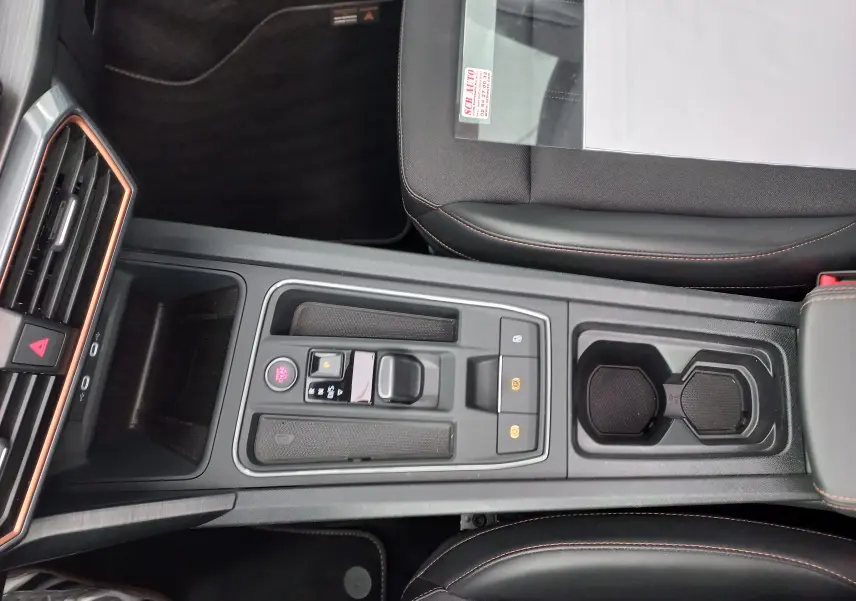Vue plongeante sur la console centrale noire du CUPRA Formentor 2024 avec surpiqûres orange et commandes électroniques.