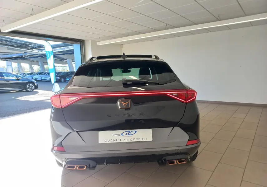 Vue arrière d'un CUPRA Formentor noir minuit avec feux LED en bandeau et double sortie d'échappement cuivrée.