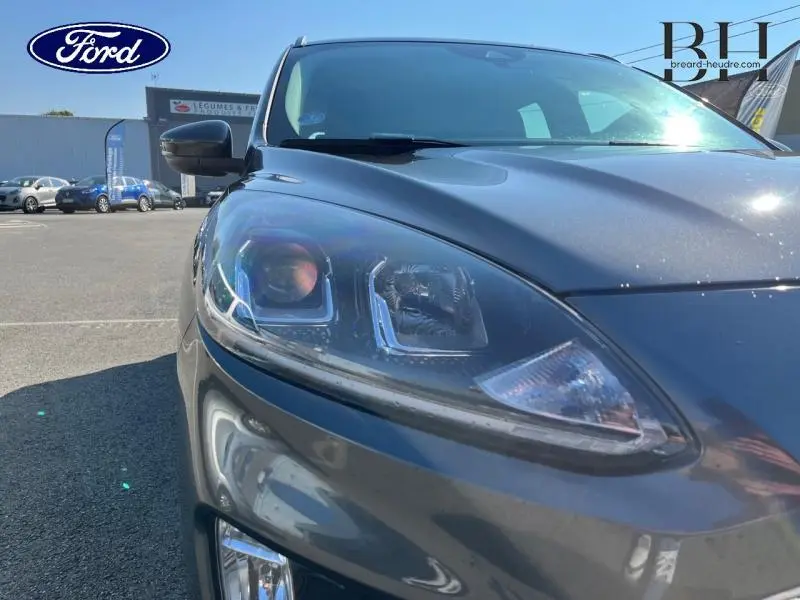 Gros plan sur le phare avant gauche du Ford Kuga gris métallisé, mettant en valeur le design moderne et les détails lumineux.