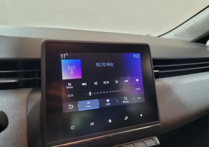 Écran tactile central de la Renault Clio gris foncé affichant la radio FM à 90,70 MHz dans l'habitacle.