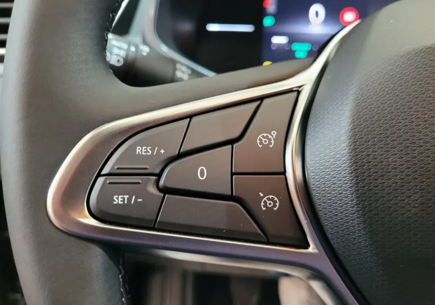 Gros plan sur les commandes du régulateur de vitesse au volant cuir de la Renault Clio gris foncé Evolution Blue dCi 100 2025.