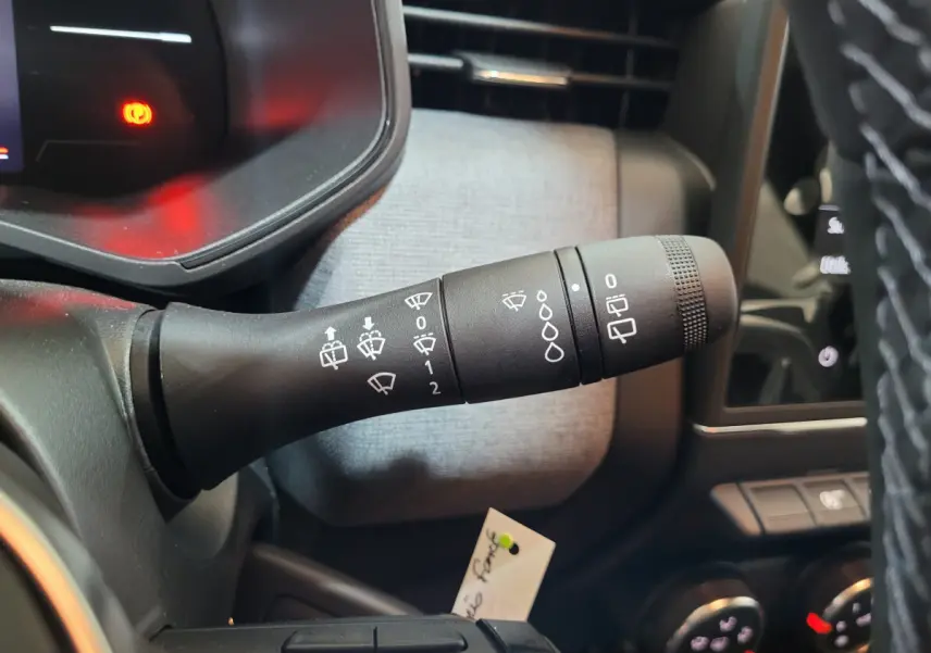 Gros plan sur la commande d’essuie-glace à gauche du volant dans l’habitacle gris foncé d’une Renault Clio 2025.