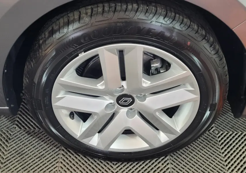 Gros plan sur la roue arrière droite d'une Renault Clio gris foncé, mettant en valeur le pneu et l'aile du véhicule.