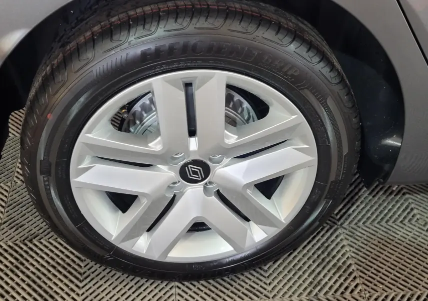 Gros plan sur la roue arrière droite d'une Renault Clio gris foncé, montrant le pneu et l'aile du véhicule.
