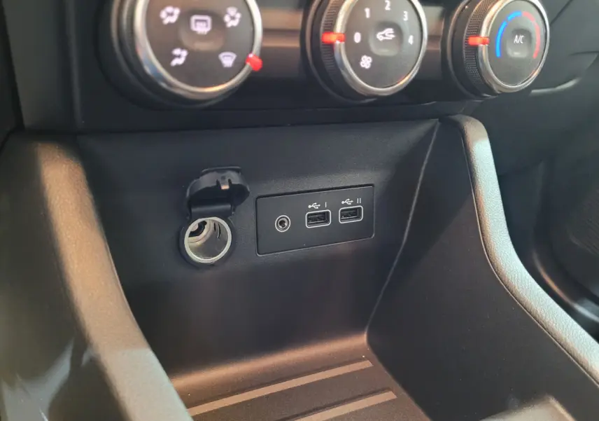 Gros plan sur la console centrale noire de la Renault Clio gris foncé, montrant les commandes de climatisation et ports USB.