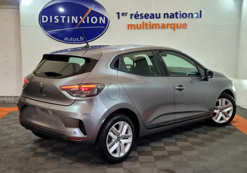 Renault Clio Evolution Blue dCi 100 2025 gris foncé vue 3/4 arrière droit avec feux LED allumés en intérieur showroom.