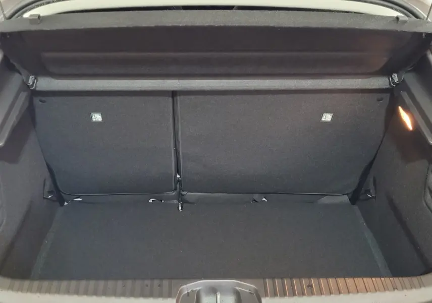 Coffre ouvert vu de l'arrière d'une Renault Clio gris foncé, montrant l'espace de chargement et la banquette arrière.