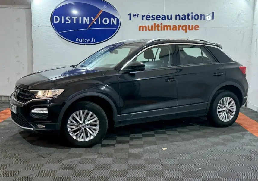 Volkswagen T-Roc noir vue de profil côté gauche dans un showroom avec logo Distinxion en arrière-plan.