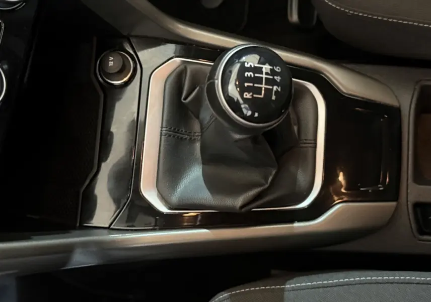 Gros plan sur le levier de vitesses manuel entouré de cuir noir dans l'habitacle du Volkswagen T-Roc 2020 noir.