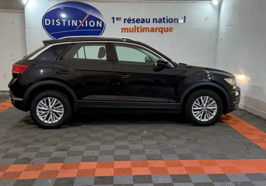 Profil côté gauche d'un Volkswagen T-Roc noir 2020 garé en intérieur avec jantes alliage et rails de toit noirs.