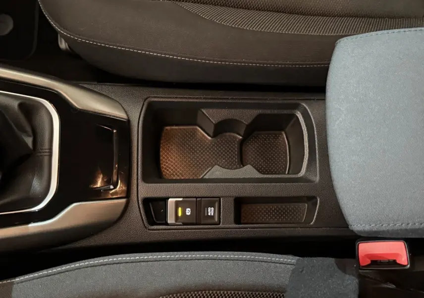 Gros plan sur la console centrale noire du Volkswagen T-Roc 2020, montrant le frein à main électrique et porte-gobelets.