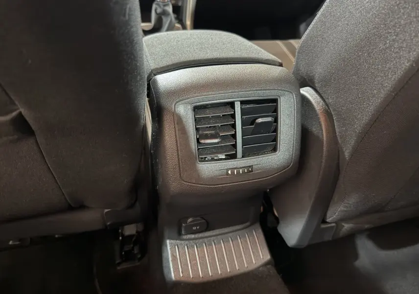 Bouche d'aération arrière et prise 12V entre les sièges noirs du Volkswagen T-Roc 2020 vue de l'intérieur arrière.