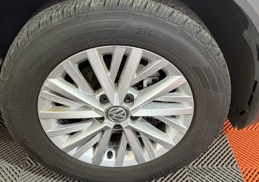 Gros plan sur la roue avant droite du Volkswagen T-Roc noir, mettant en valeur la jante alliage à rayons multiples.