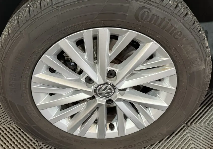 Gros plan sur la jante argentée en alliage d'une Volkswagen T-Roc noire, mettant en valeur le logo VW central.