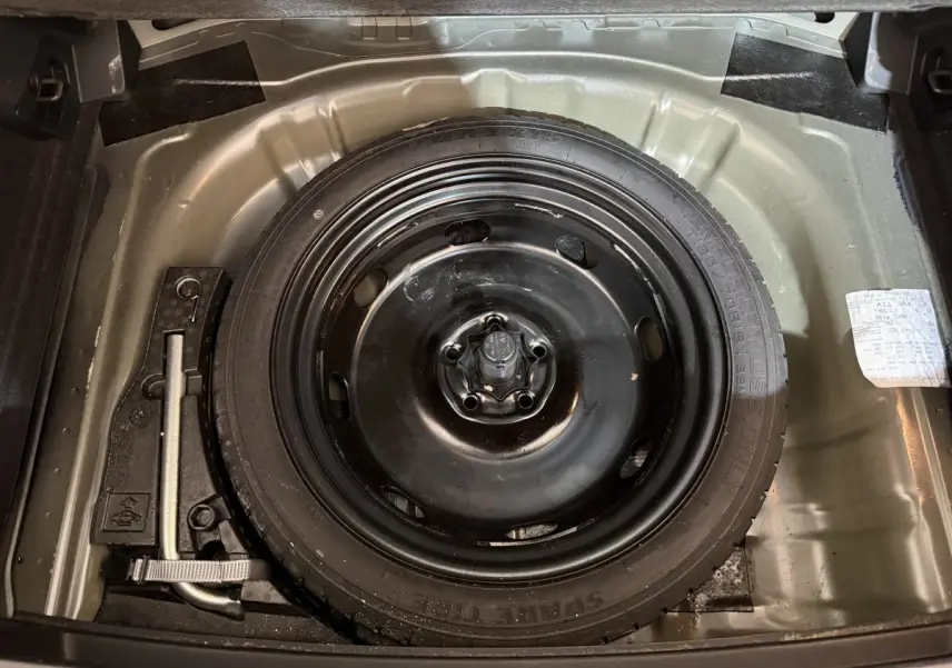 Vue plongeante sur la roue de secours noire dans le coffre d'un Volkswagen T-Roc noir 2020.