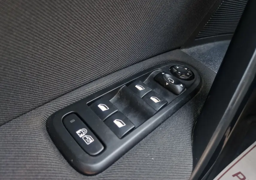 Gros plan sur les commandes des vitres électriques côté gauche d'une Peugeot 508 SW gris Shark, intérieur tissu noir.