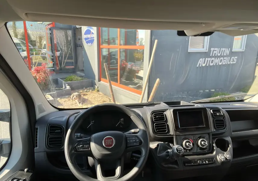 Vue intérieure du tableau de bord et volant noir du Fiat Ducato Fourgon 2023 avec boîte manuelle et écran central.