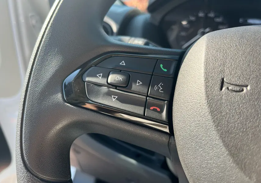 Gros plan sur les commandes de téléphonie et navigation au volant du FIAT Ducato Fourgon blanc 2023 côté gauche.