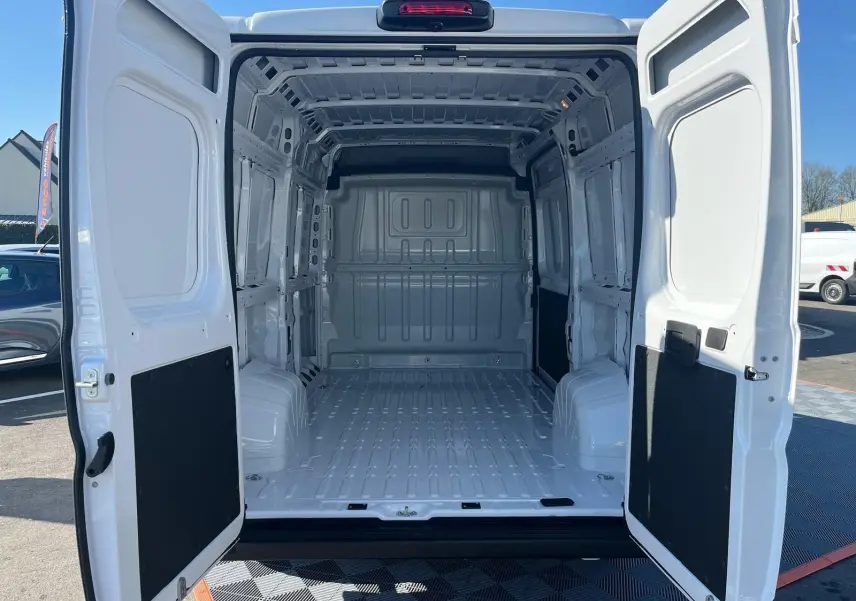 Vue arrière du FIAT Ducato Fourgon blanc 2023 avec portes ouvertes dévoilant l'espace de chargement vide et spacieux.
