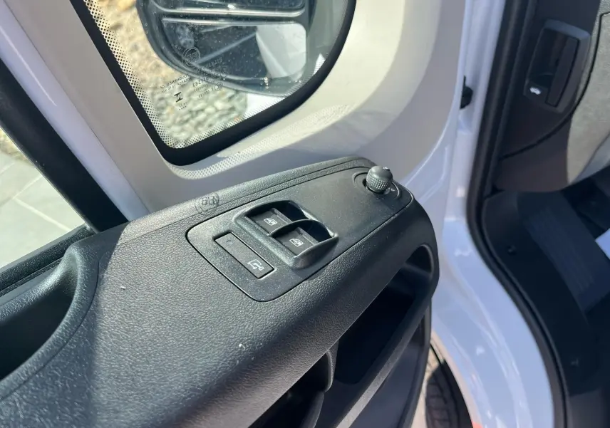 Détail des commandes des vitres sur la porte côté conducteur du FIAT Ducato Fourgon blanc 2023, vue rapprochée.