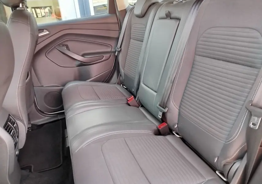 Vue latérale intérieure des sièges arrière gris foncé en tissu et cuir du Ford Kuga 2019, avec ceinture de sécurité visible.