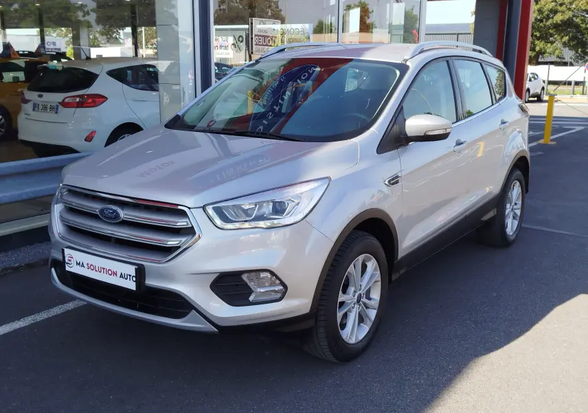 Ford Kuga gris clair vu en 3/4 avant droit, avec calandre chromée et jantes alliage 17 pouces.