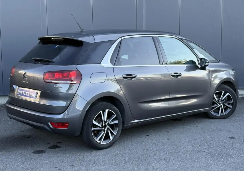 Vue 3/4 arrière côté droit d'une Citroën C4 Picasso gris Platinium avec jantes alliage bi-ton et hayon électrique.