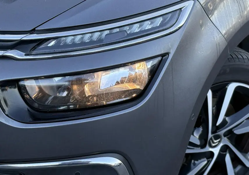 Gros plan sur l'avant droit gris Platinium d'une Citroën C4 Picasso 2017, avec phare LED et jante alliage bi-ton.