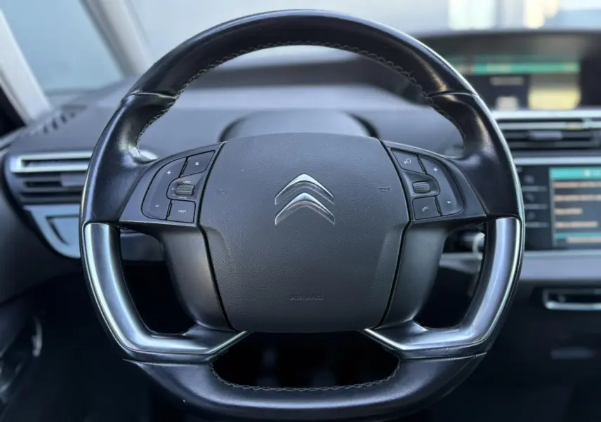 Gros plan sur le volant cuir noir du Citroën C4 Picasso 2017 avec commandes intégrées et logo chromé central.