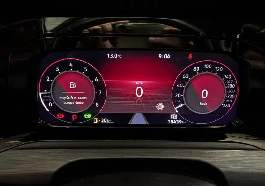 Combiné d'instruments numérique rouge du tableau de bord de la Volkswagen Golf noire 2024, affichant vitesse et consommation.
