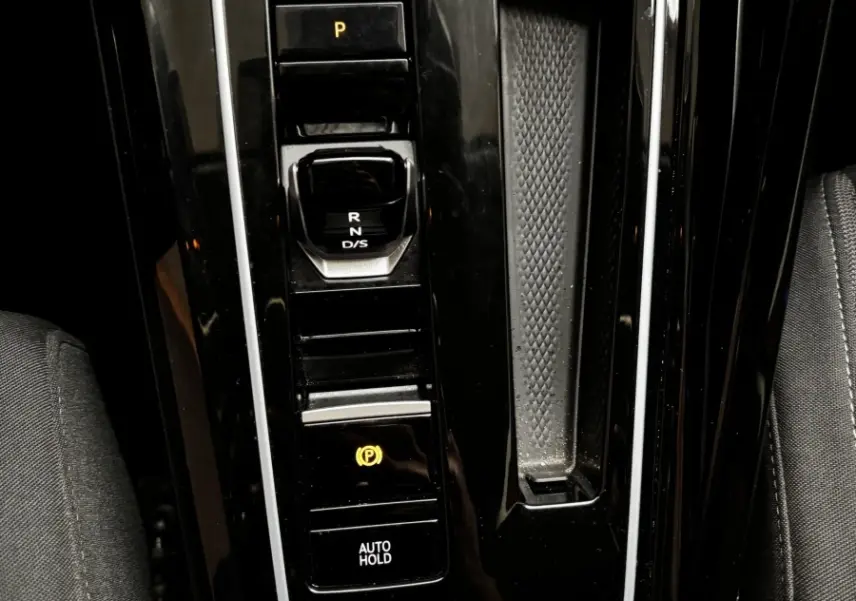 Vue rapprochée de la console centrale noire de la Volkswagen Golf 1.5 ETSI OPF 130 DSG7 Style avec sélecteur de boîte auto et boutons lumineux.