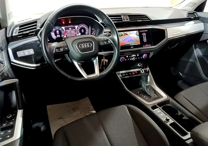 Vue intérieure côté conducteur de l'Audi Q3 35 TDI Business Line 2020 avec tableau de bord numérique et écran tactile central allumé.