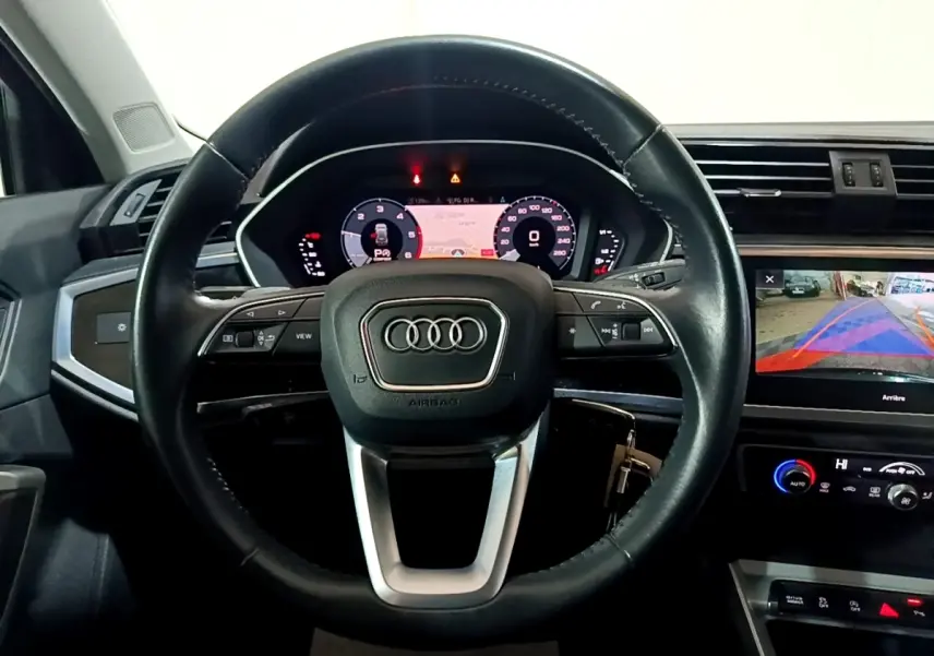 Vue intérieure centrée sur le volant cuir noir et le tableau de bord digital de l'Audi Q3 35 TDI Business Line 2020.