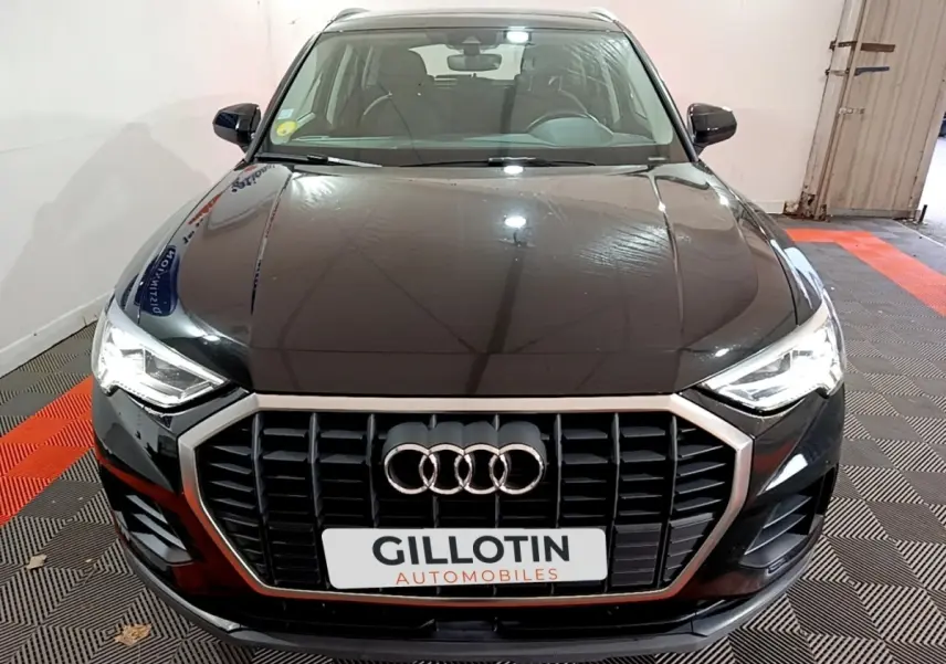 Vue avant d'un Audi Q3 noir 2020 avec calandre chromée et phares LED allumés dans un garage.